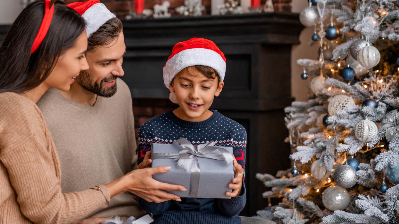 Woman Tells People To Stay Humble Before Posting Pictures Of Piles Of Christmas Gifts Parents giving present their son while sitting near Christmas tree in living room.