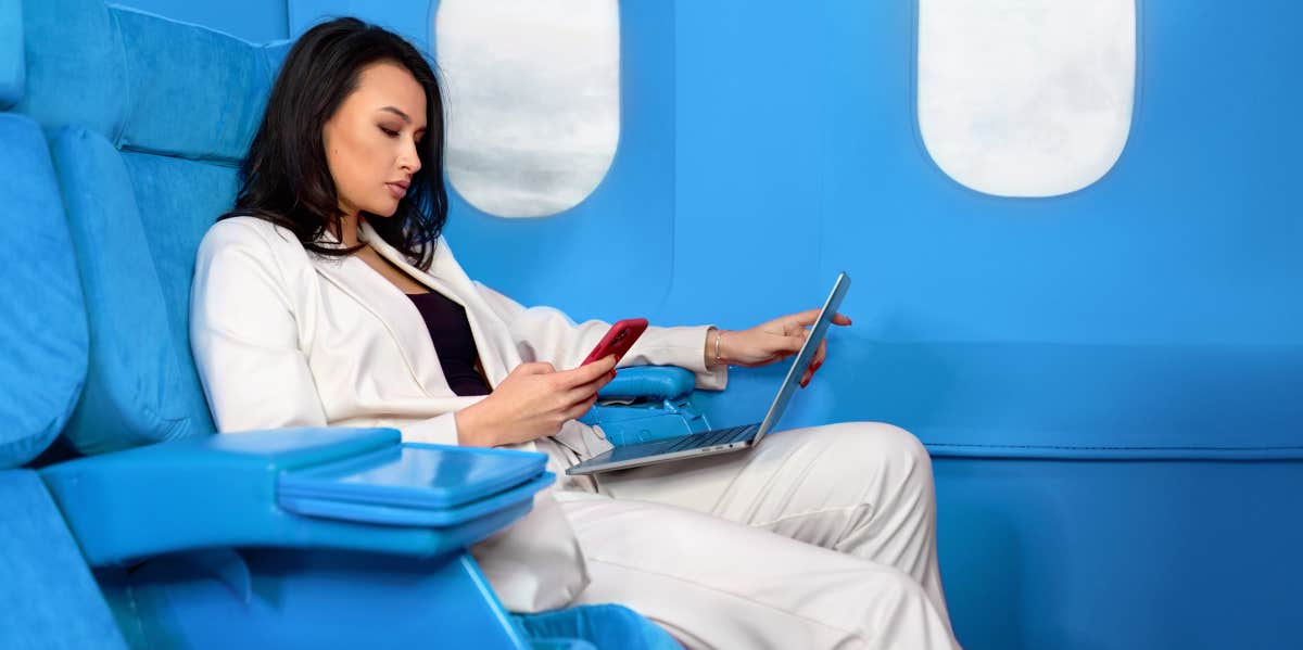 woman seated in first class seat working on laptop