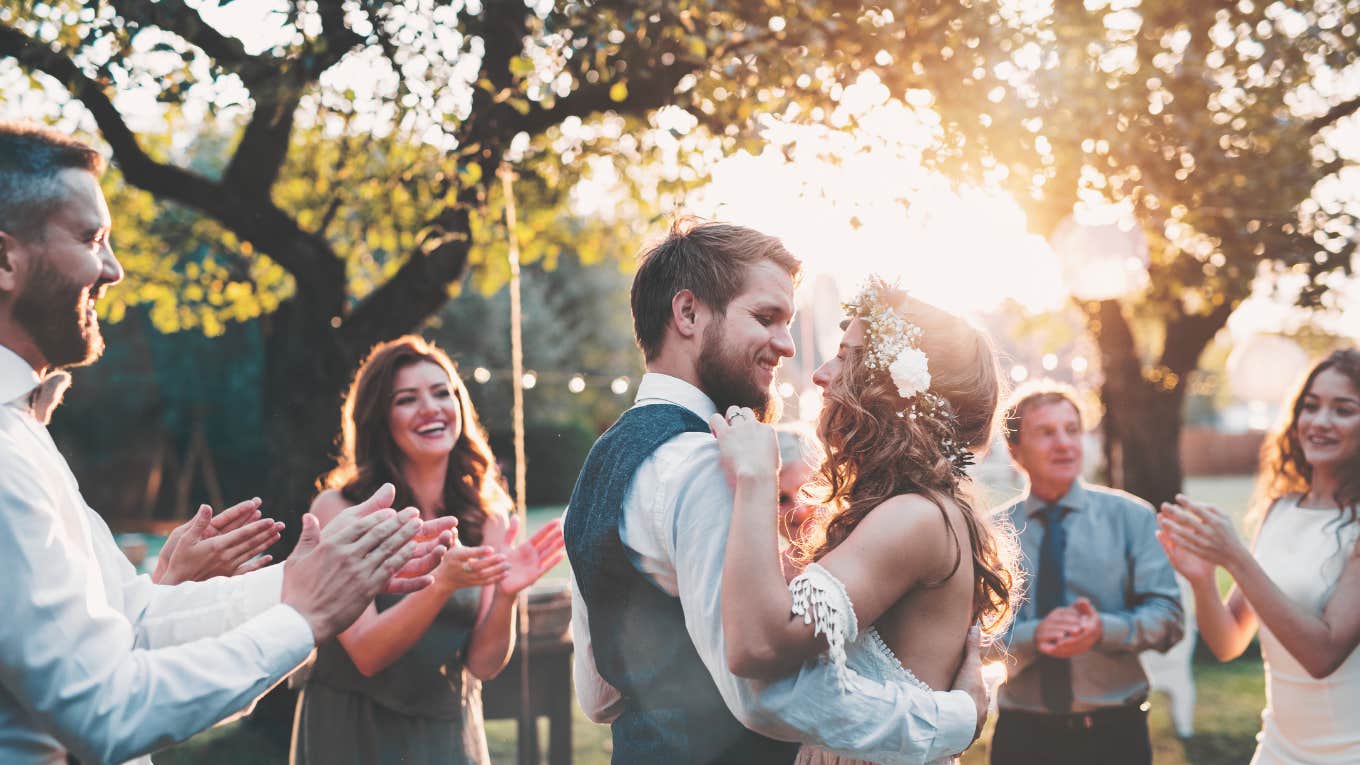 Bride and groom dancing at wedding reception outside in the backyard.