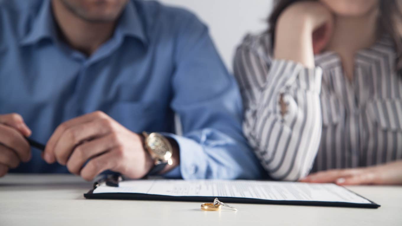 couple signing divorce papers with rings on the table