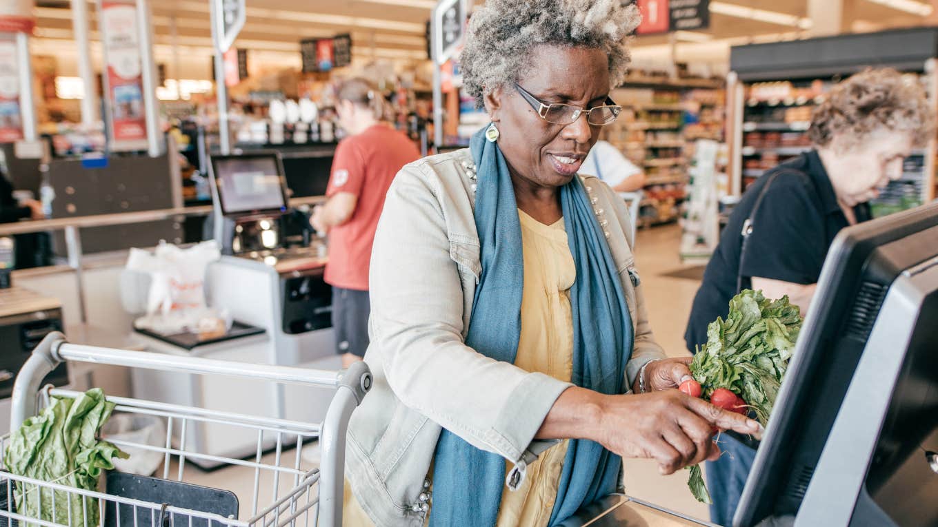 Woman looks confused while standing at a grocery self-check out. 