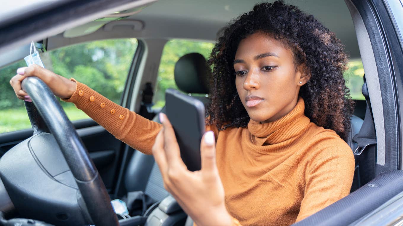 woman in car looking at phone