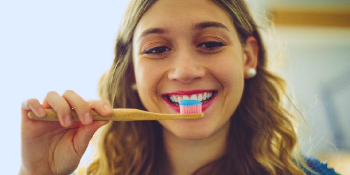 woman brushing her teeth smiling