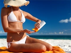 woman bikini applying lotion beach