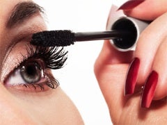 woman wearing lots of makeup putting on mascara