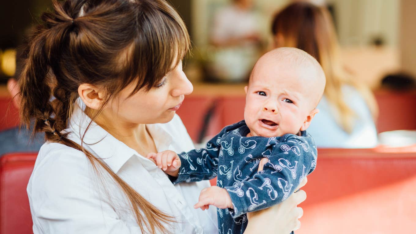 Mother calming down her crying baby at a resaurant