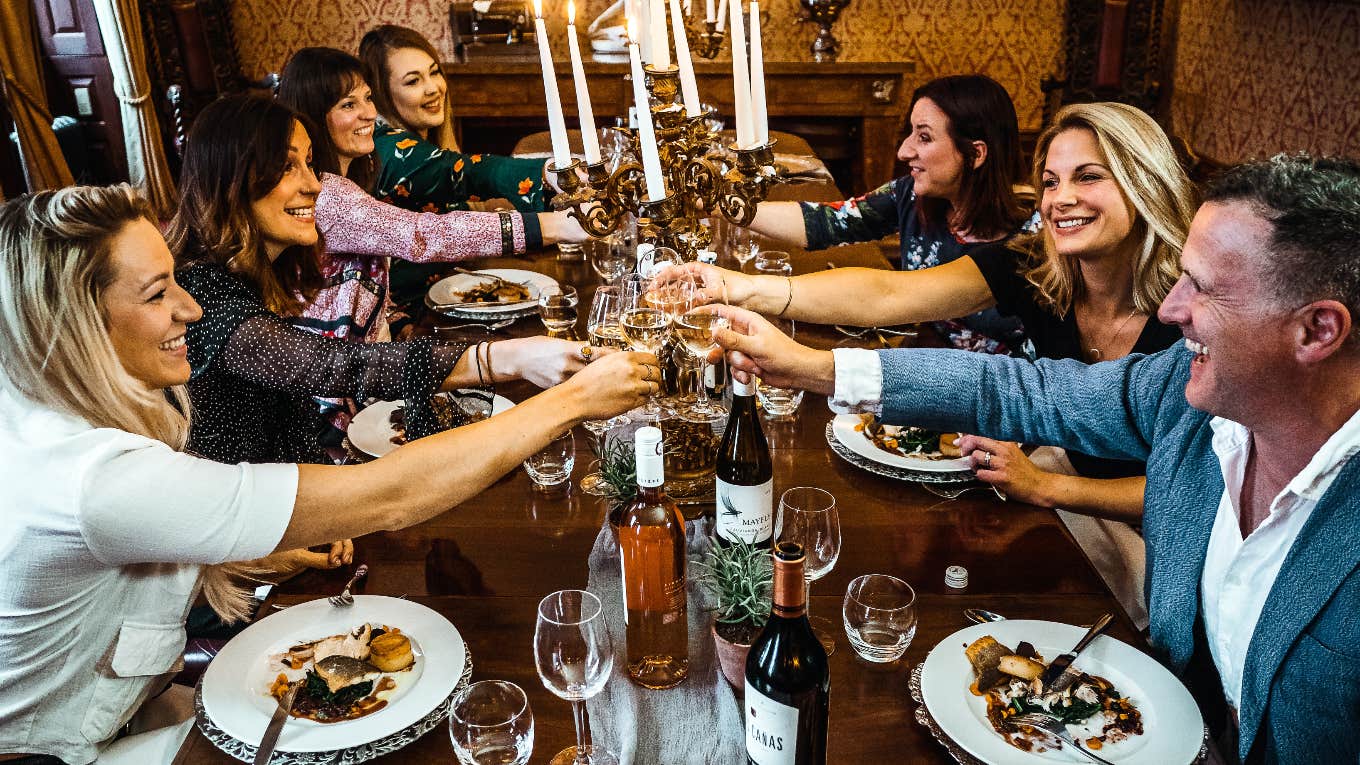 group of people cheersing glasses at dinner table