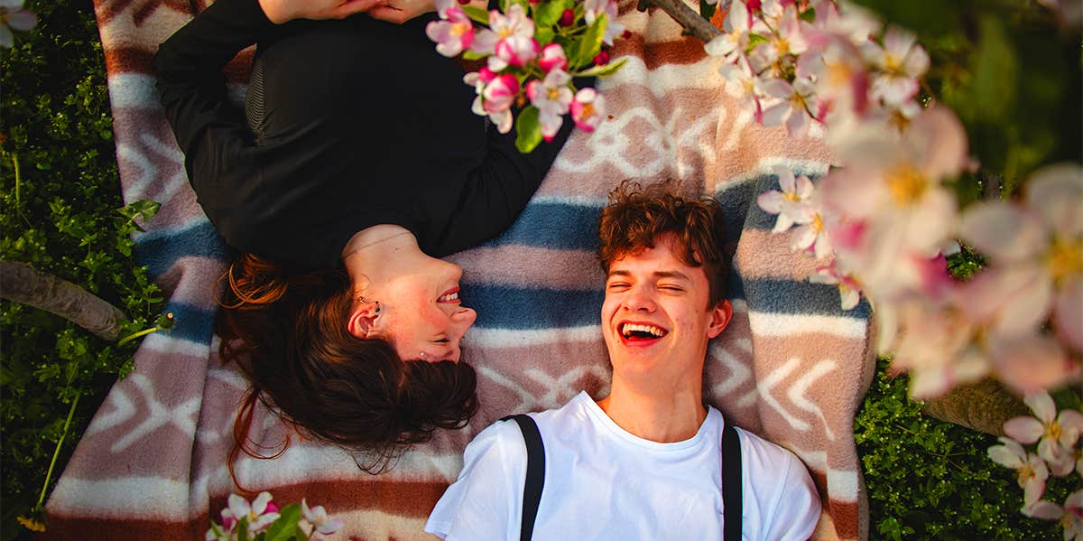 man and woman laying on blanket outside