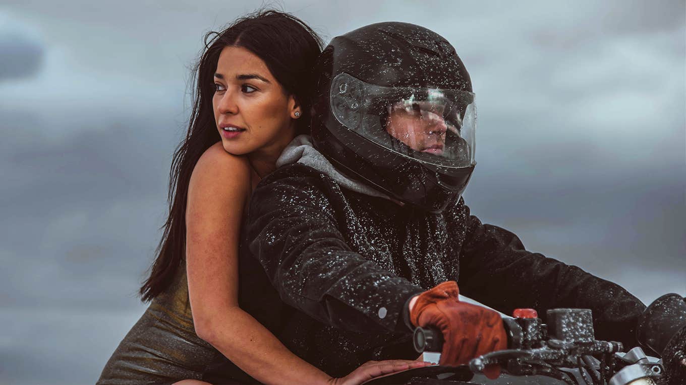 confident woman riding on the back of her boyfriend's motorcycle