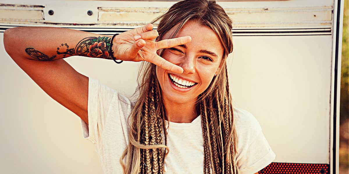 Happy woman with bohemian braided hair smiling and making a peace sign 