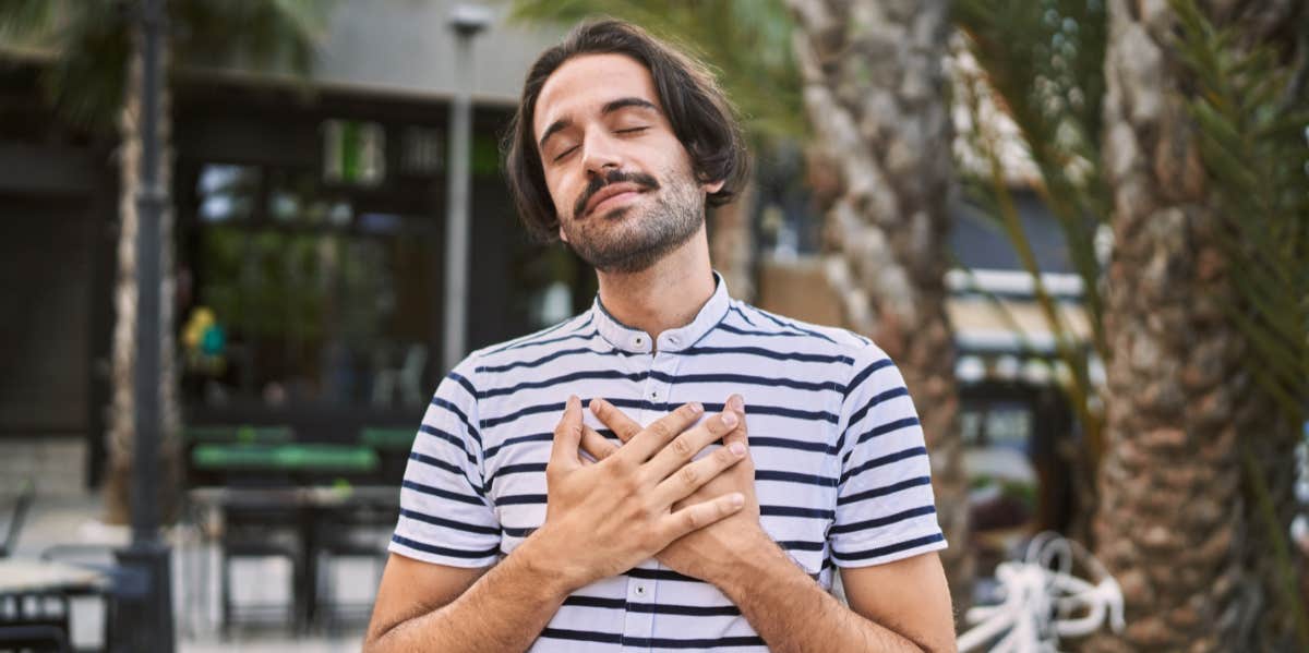 man with eyes closed holding his heart
