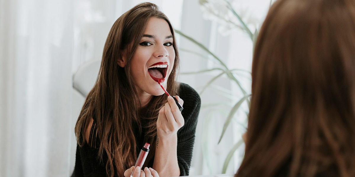 woman putting on red lipstick