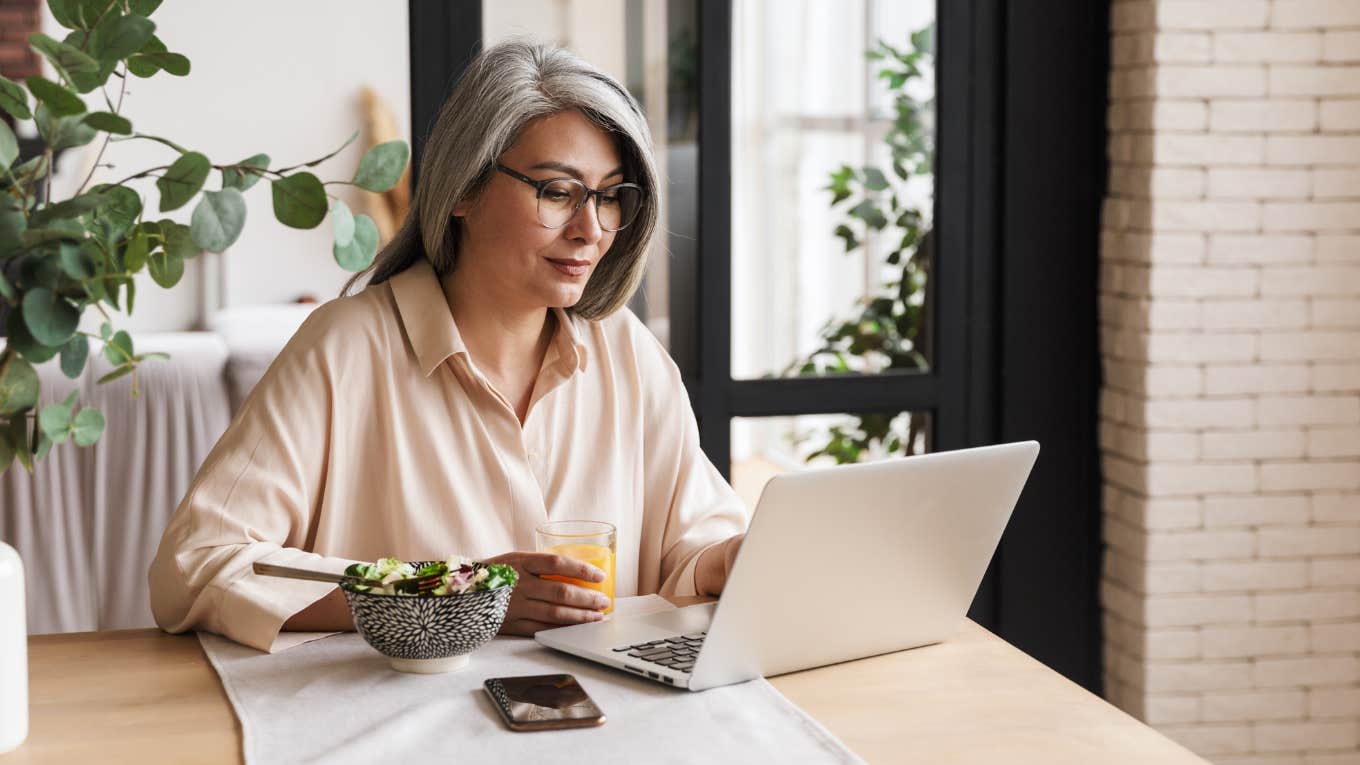 Woman smiles while looking at her laptop. 