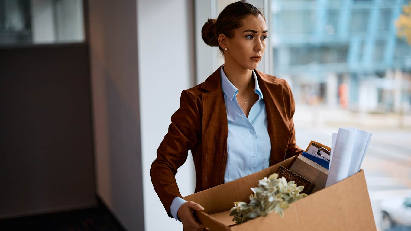 woman carrying box of office items after being fired