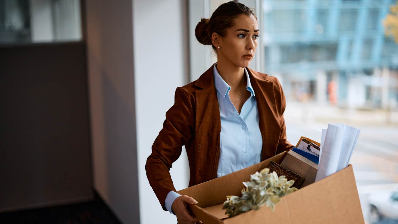Worker Shares Negative Performance Reviews Before Being Laid Off woman carrying box of office items after being fired