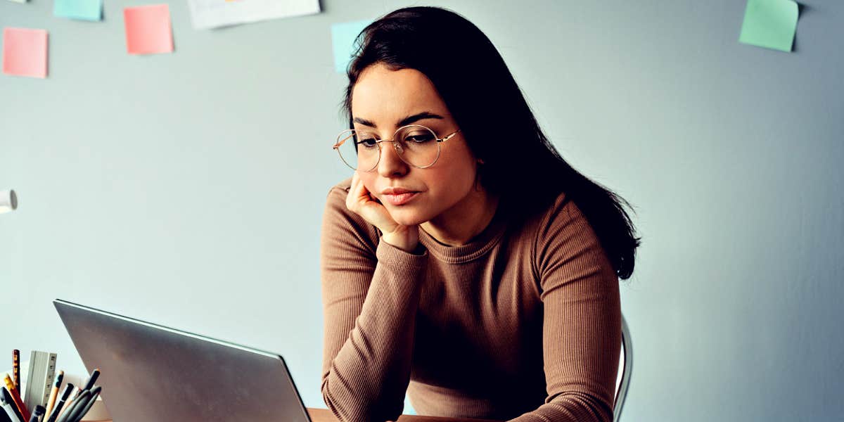 how to know if you have workplace trauma Woman looking frustrated at work with a laptop