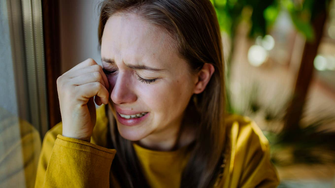 Woman sitting in hotel room alone, crying after breakup 