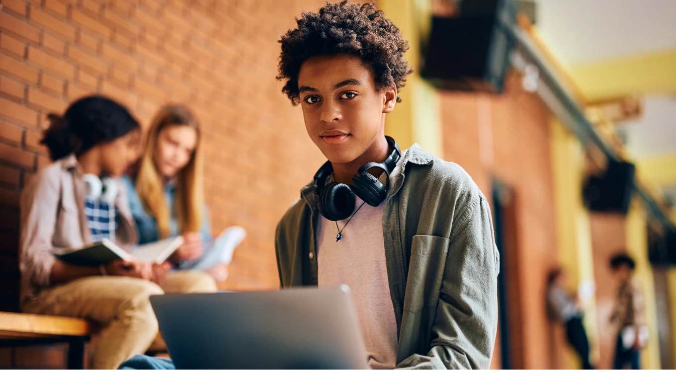 Young boy sitting with his laptop at school