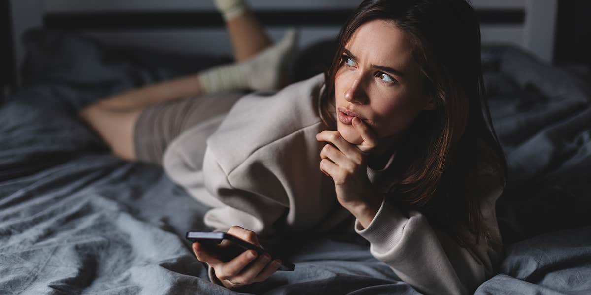 woman laying in bed on phone