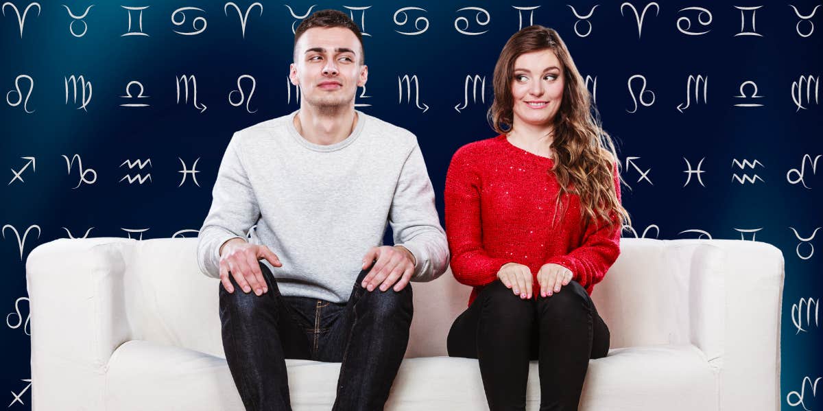 awkward couple sitting on couch in front of zodiac signs