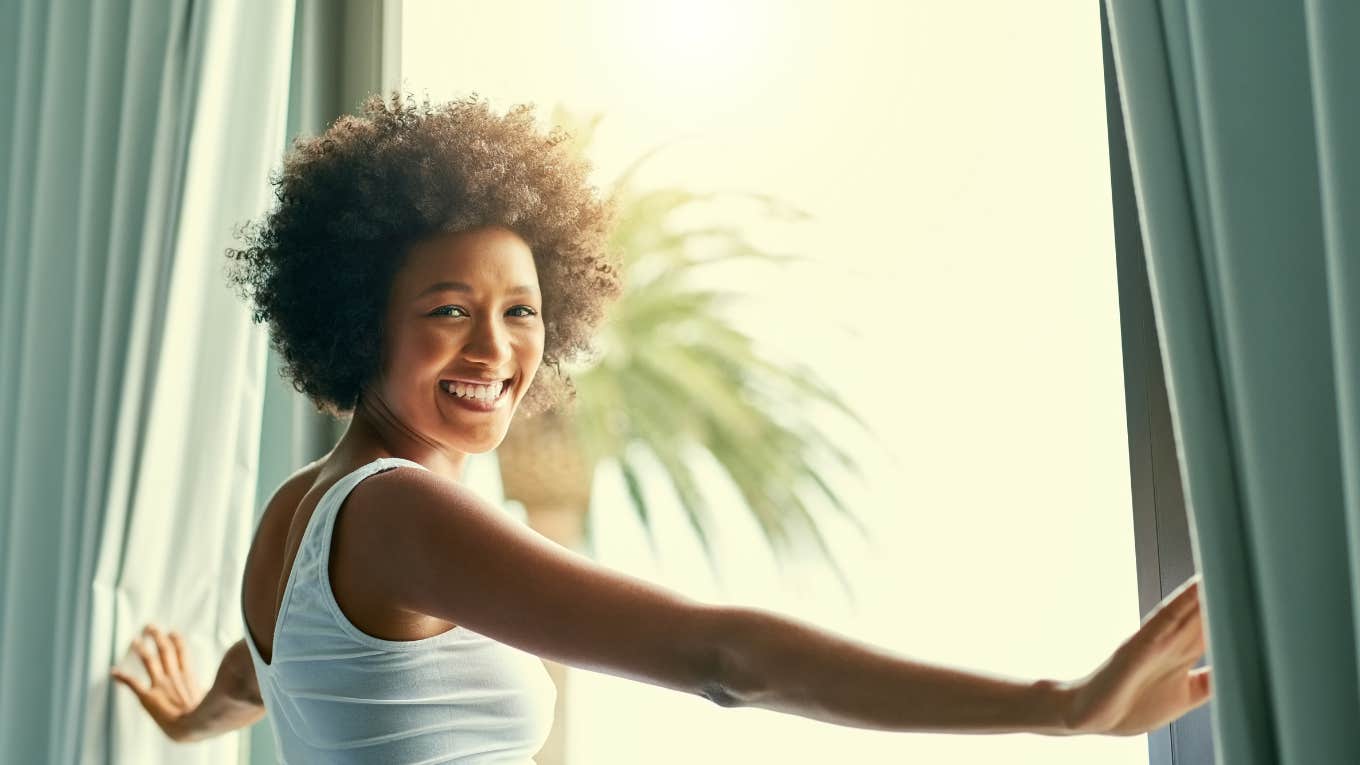 woman smiling while looking out a window