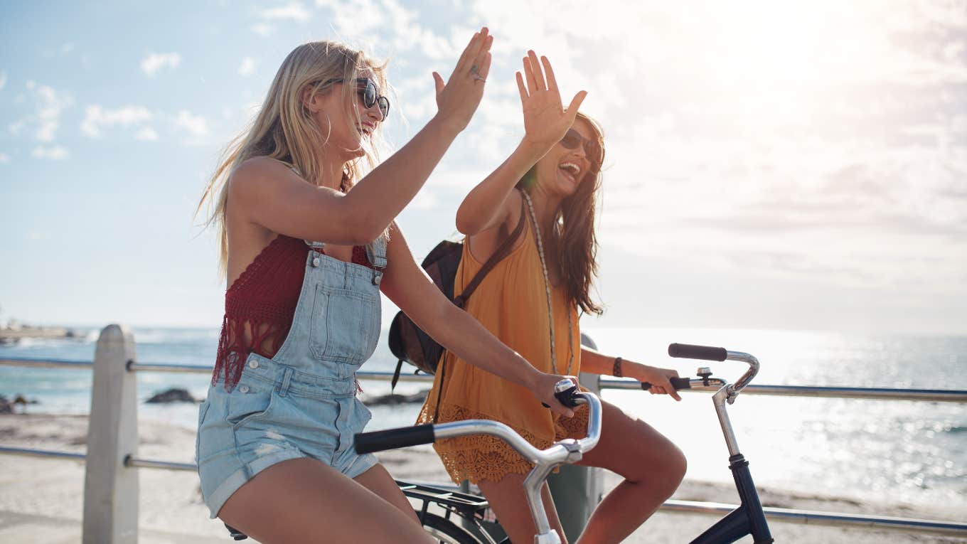 two girls riding a bike on the beach