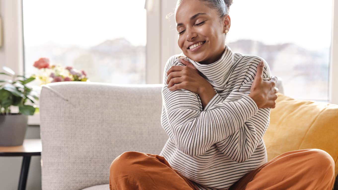 woman hugging herself while on sofa