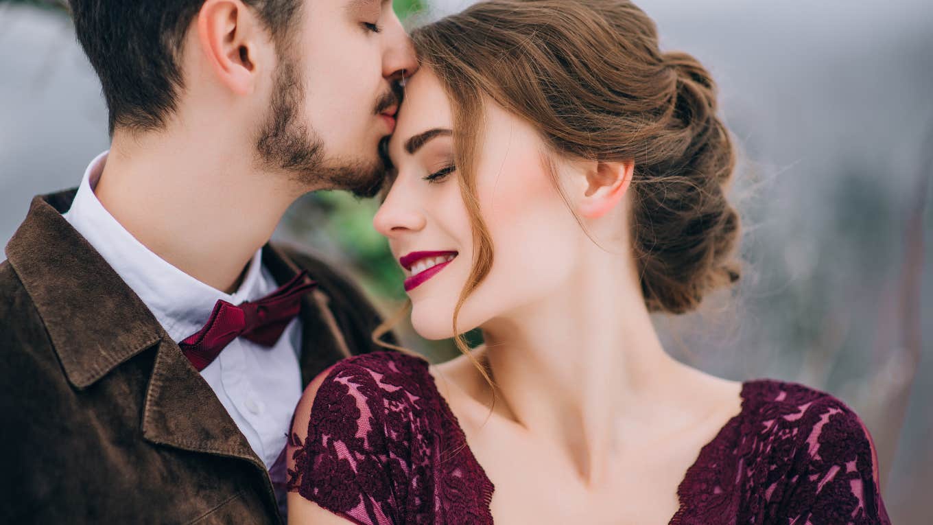 man kissing woman on forehead