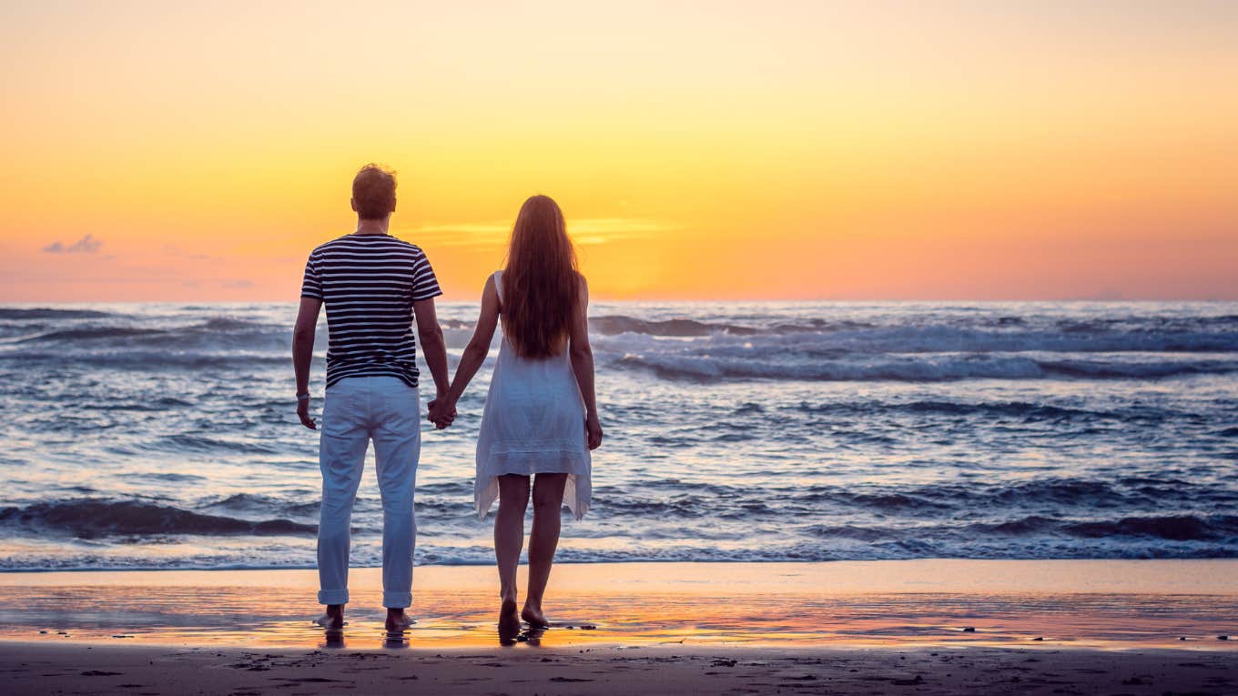couple standing by ocean holding hands