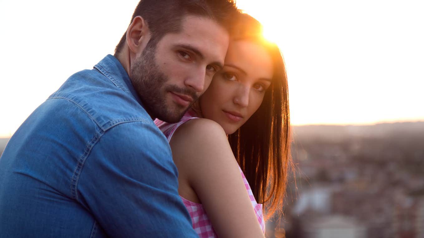 man and woman in a warm embrace looking at the camera