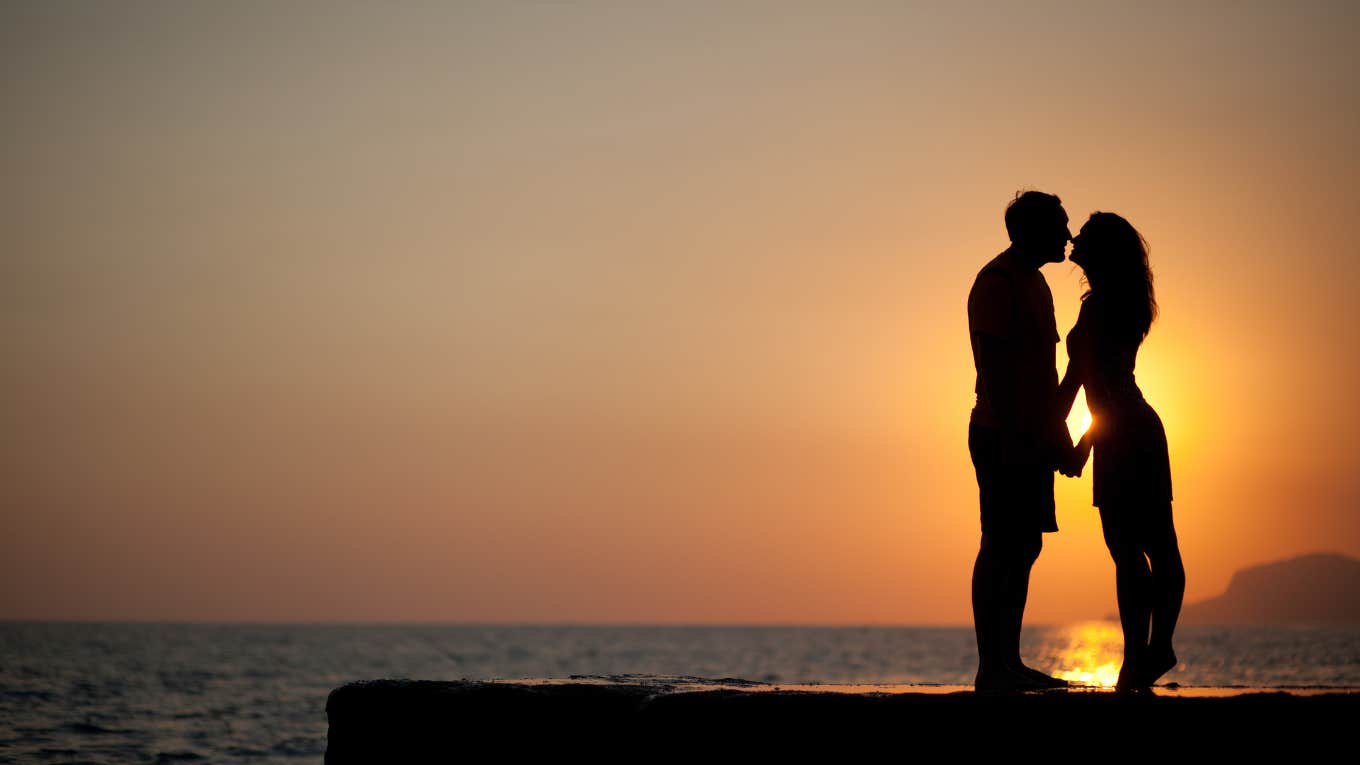 man and woman romantically holding hands on beach