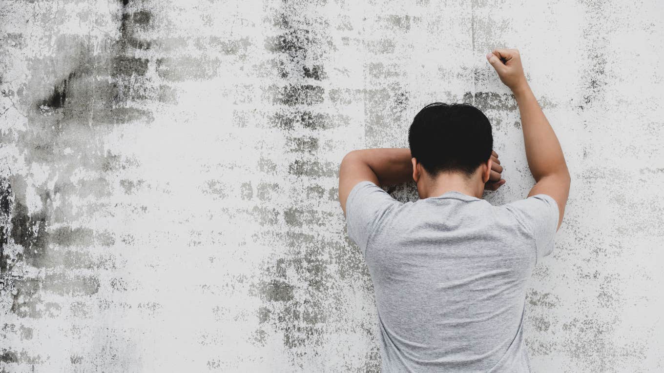 sad man leaning against wall