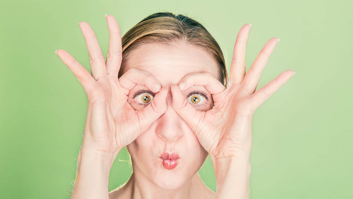 woman making a silly face using hands as glasses