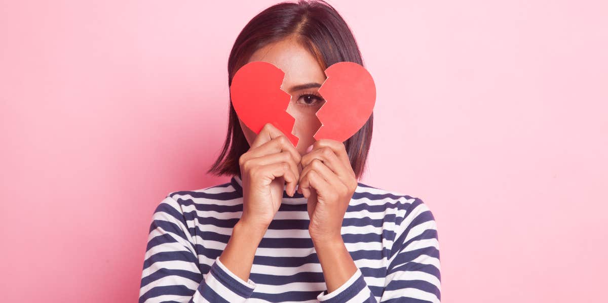 woman hiding behind broken heart