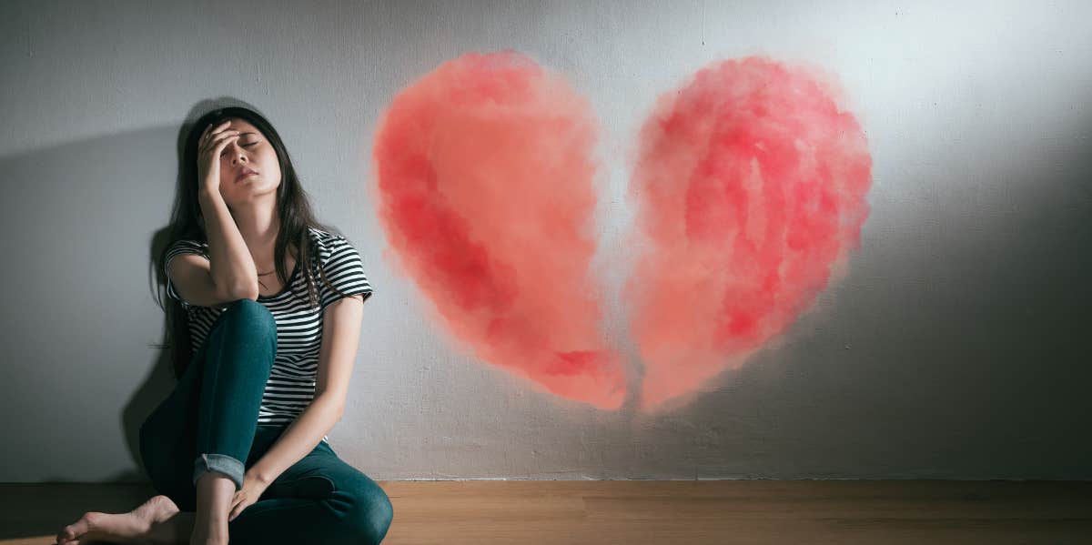 woman sitting next to a broken heart