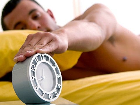 man touching alarm clock