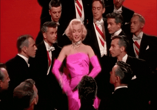 Marilyn Monroe in a hot pink gown surrounded by suitors in "Gentlemen Prefer Blondes"
