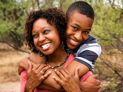 man hugging woman from behind and both are smiling