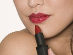 A woman applies lipstick