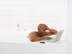 Man in bathtub with laptop