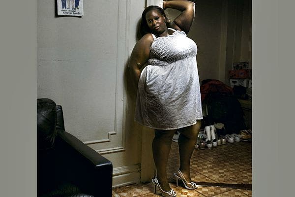 Woman leaning against wall in heels.