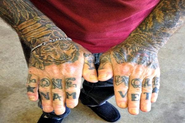 Man with lone wolf and Vietnam tattooed on his hands.