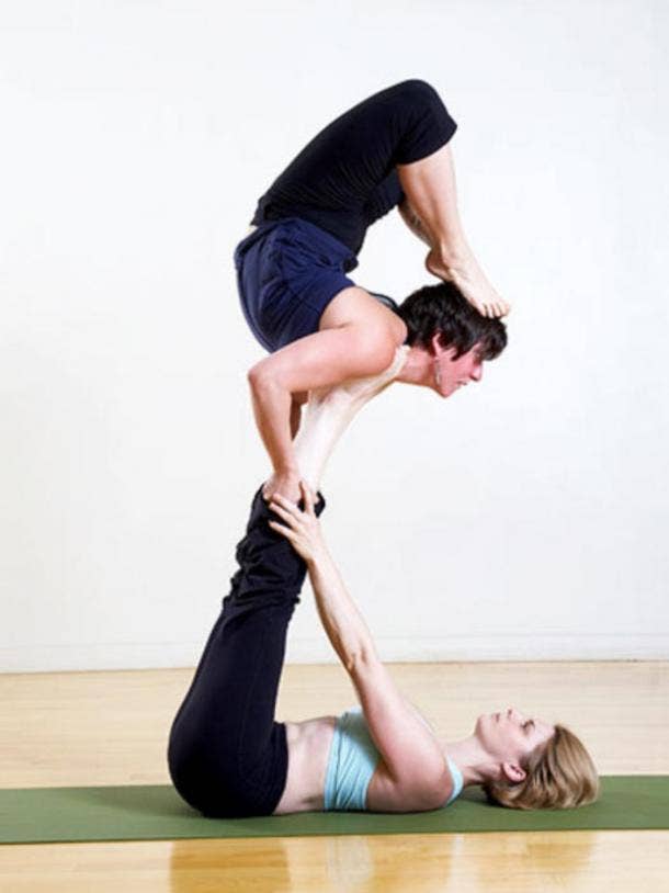 Young man and woman practicing Acro Yoga stock photo - OFFSET