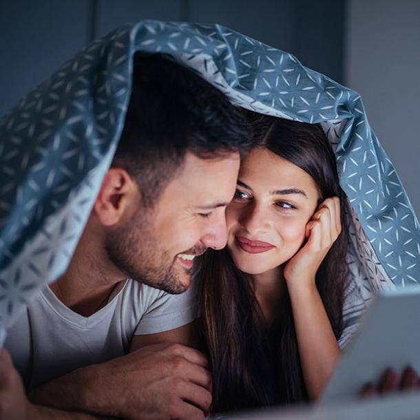 couple watching movie under covers
