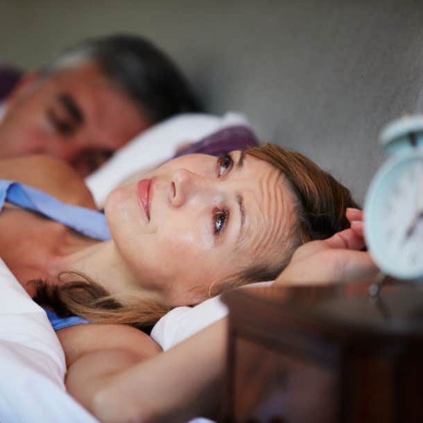 concerned woman laying in bed next to man