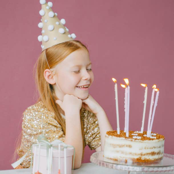 birthday girl smiling in front of birthday cake