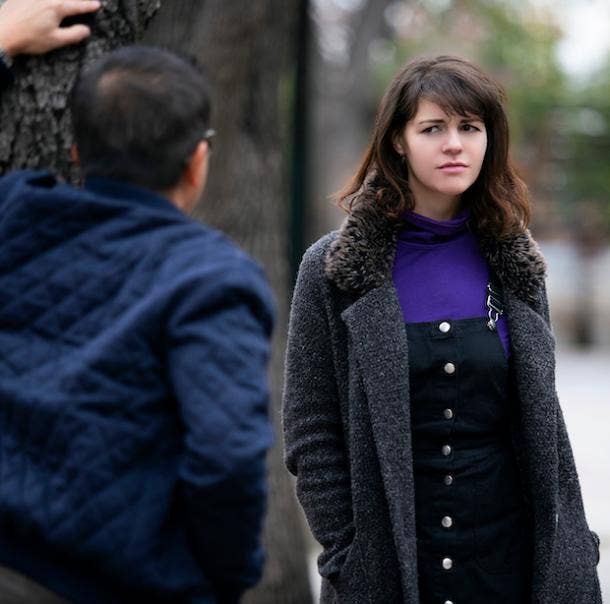 Man leans against tree looking at concerned woman