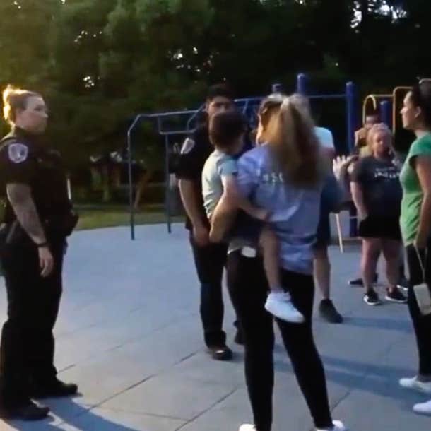 Police officers stand alongside two families arguing at a playground