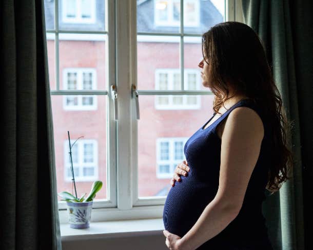 sad pregnant woman looking out the window