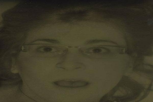 Woman in glasses, eyes wide open looks almost scared.
